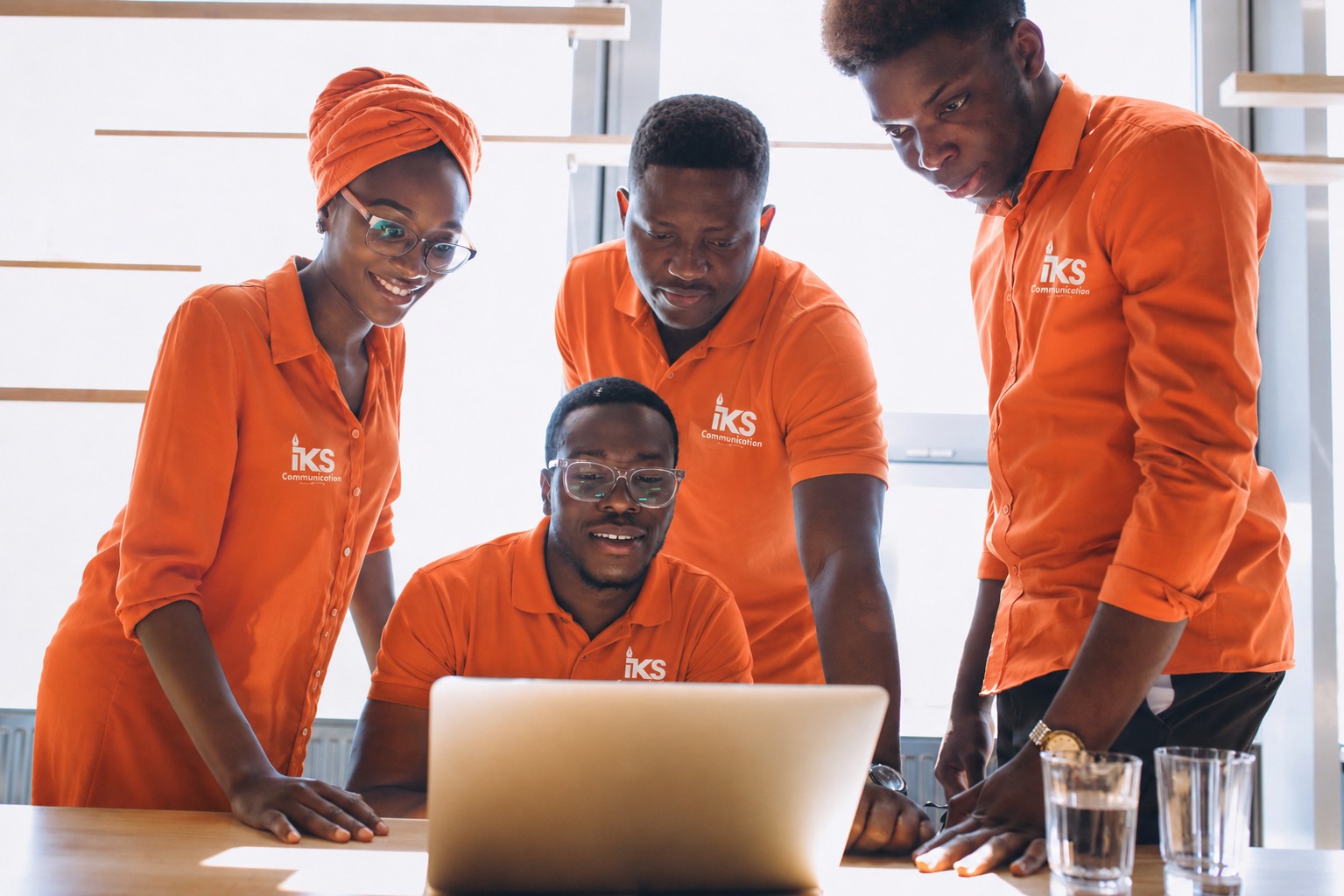 L'équipe IKS Communication en polo orange, réunie autour d'un ordinateur à Abidjan